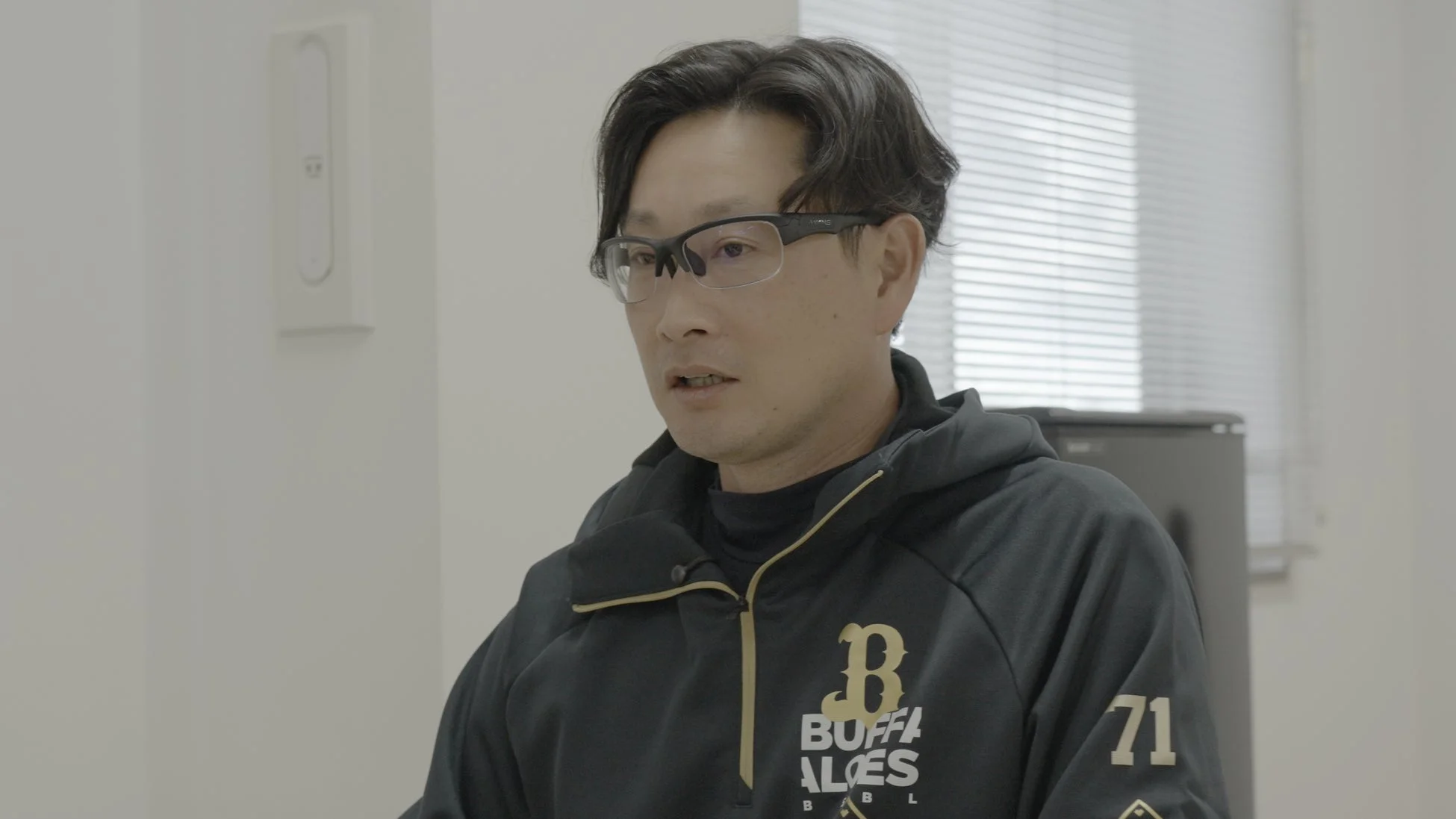 オリックス・バファローズのパーカーを着て話す男性