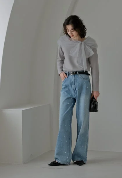 グレーのトップスに大きなリボンがあしらわれ、パール装飾のワイドデニムを合わせた女性