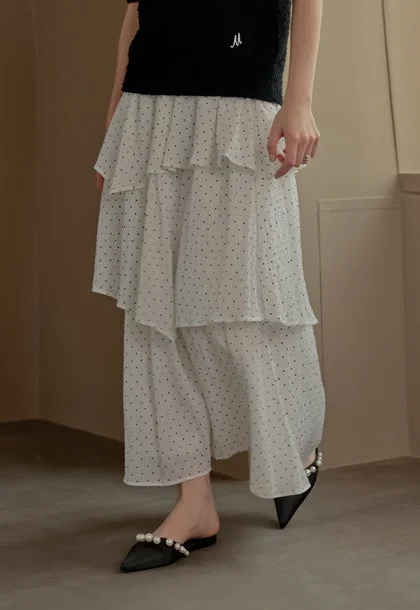 白いドット柄のティアードスカートと黒いトップスを着用した女性のファッション