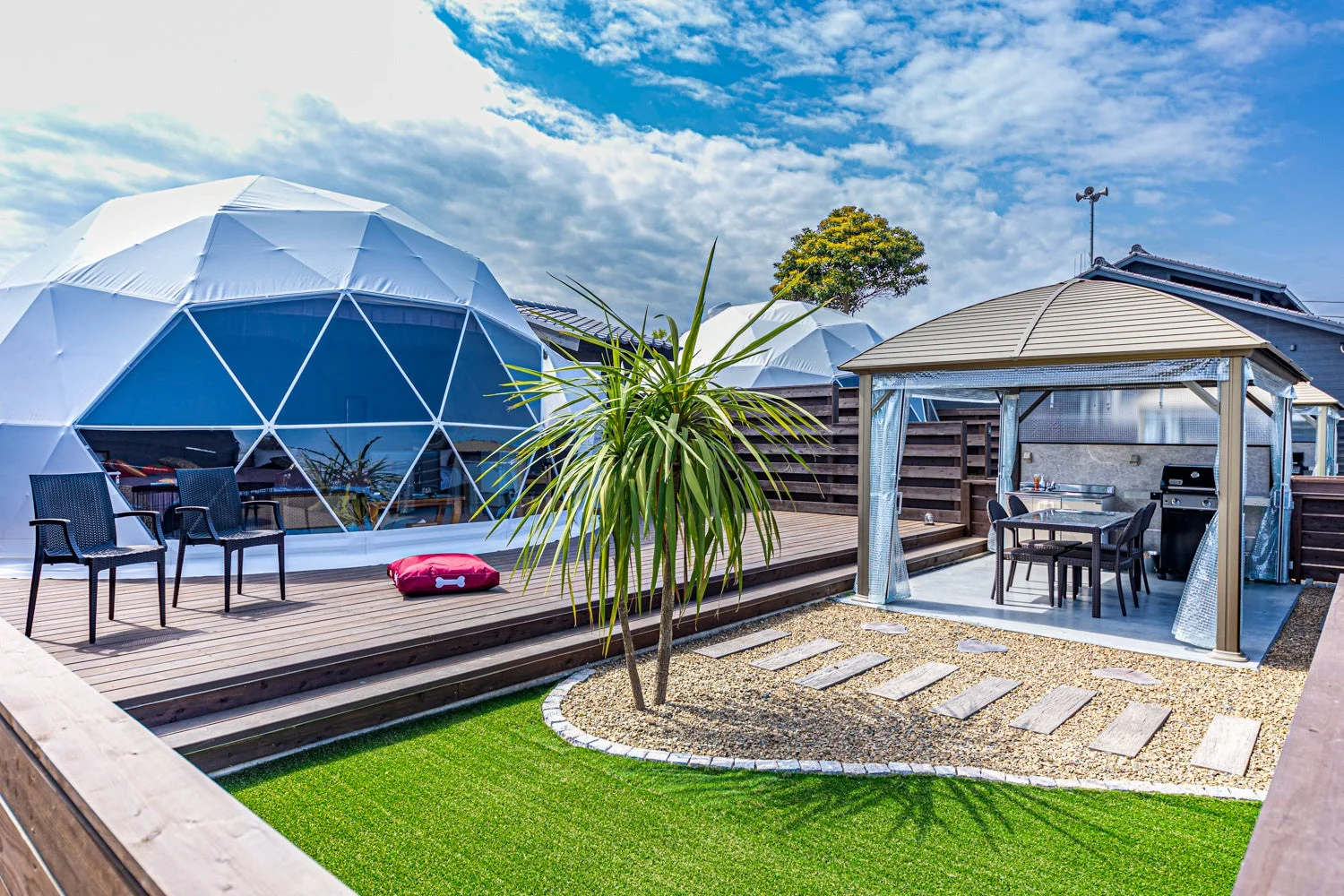 白いドーム型テントとバーベキュー設備のある屋外スペース