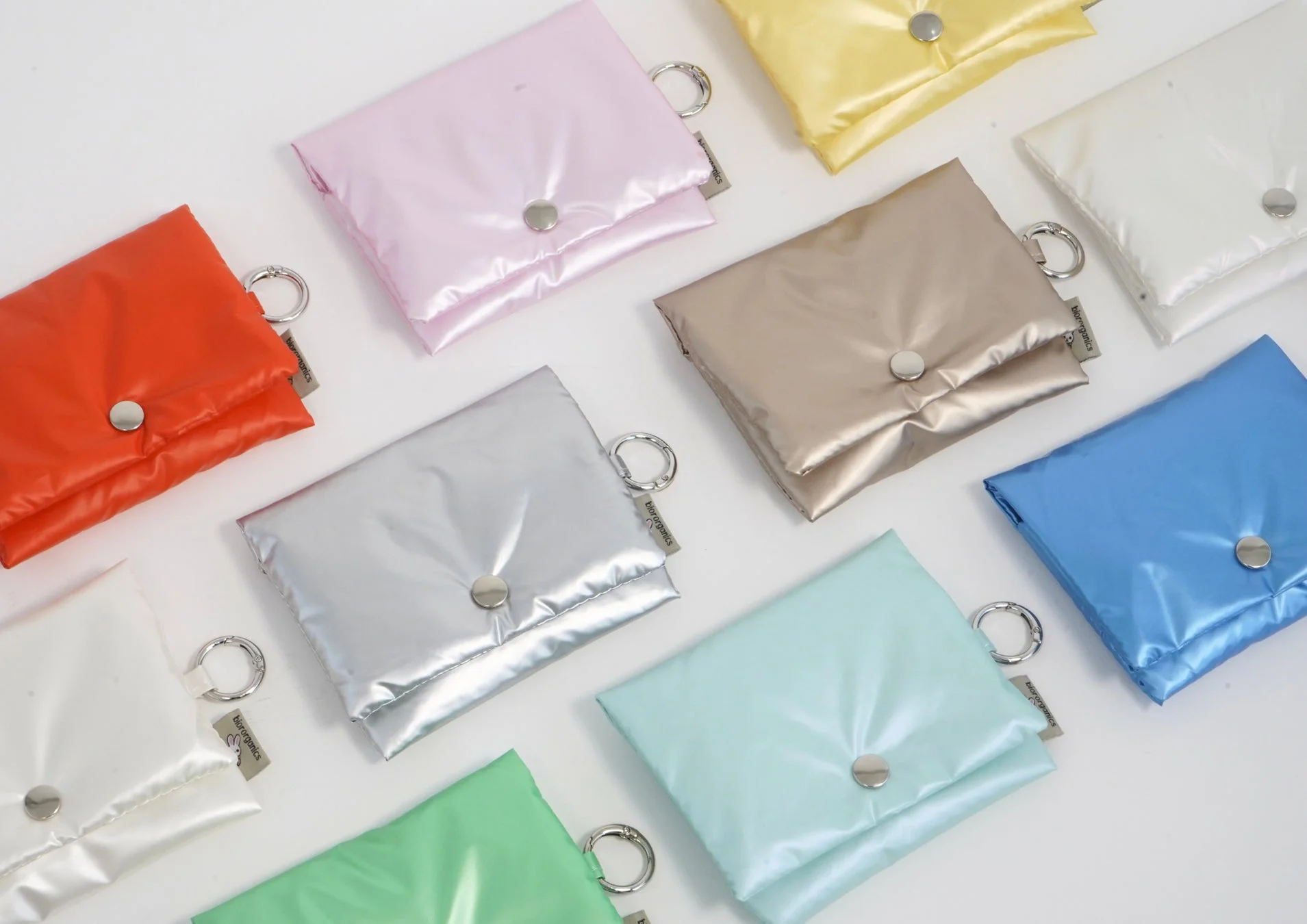 様々な色合いの光沢のあるポーチが複数並べられている