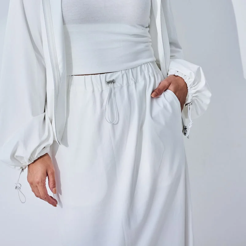 白いジャケットとボトムスを着用した人物のクローズアップ。