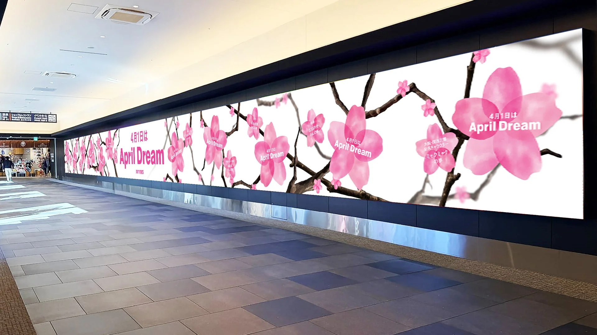商業施設の長い廊下に設置された大型デジタルサイネージの画像です。