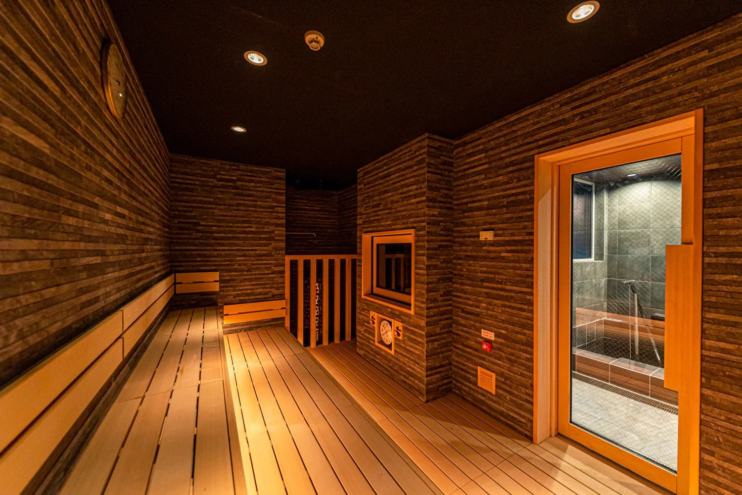 木製のベンチと壁が特徴的なモダンなサウナ室