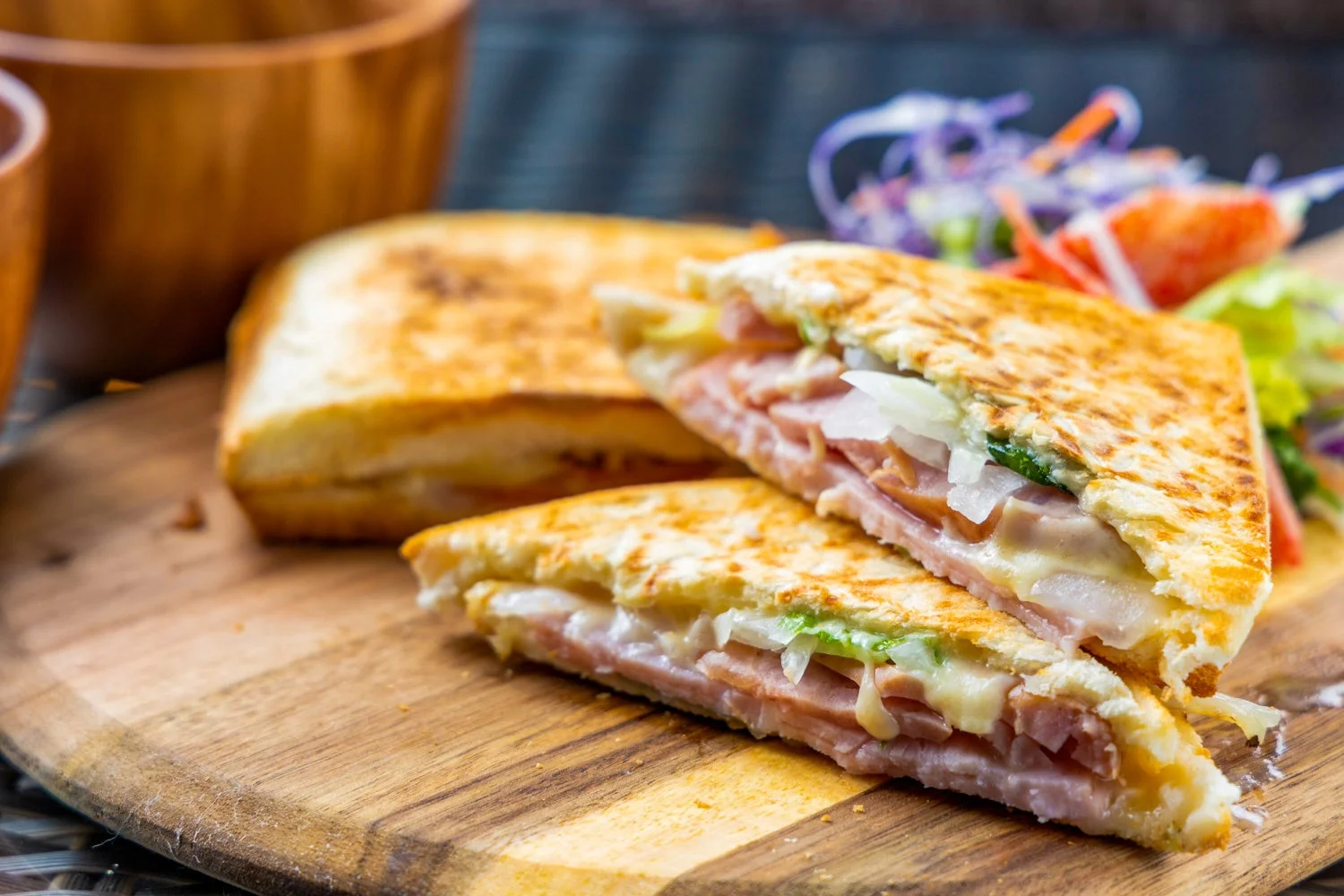 焼かれたホットサンドイッチが木製のカッティングボードに盛られた朝食