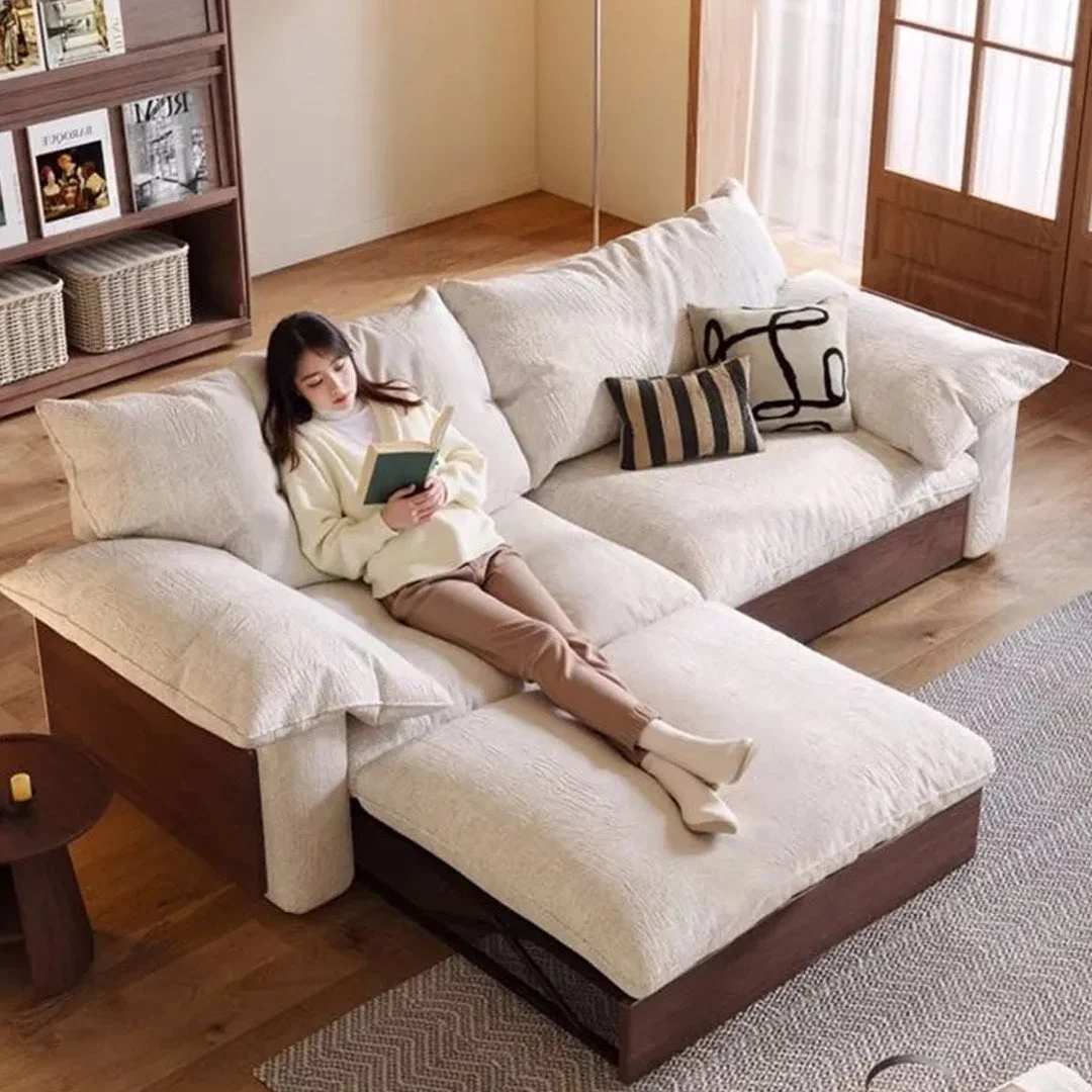 L字型ソファでくつろぐ女性が本を読んでいる様子を捉えた画像です。ナチュラルで落ち着いた色合いのリビングルームのインテリアが特徴です。