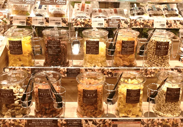 様々な種類のドライフルーツとナッツがガラス容器に並べられ、量り売りされているビュッフェコーナーの様子です。ドライマンゴー、クランベリー、ピスタチオなど豊富な品揃えで、専用のトングが用意されています。