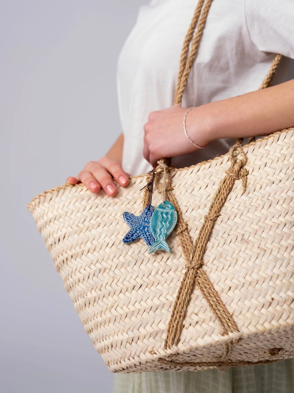 チャーム付きかごバッグを持つ女性