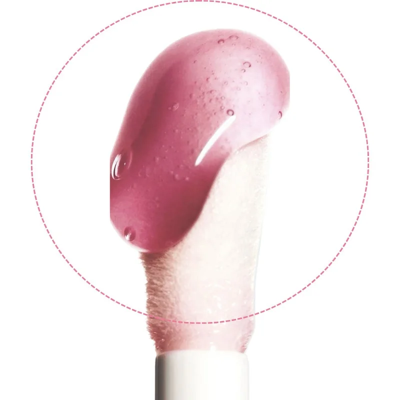 ピンク色のつややかなリップグロスがたっぷり付いたアプリケーターのクローズアップ画像