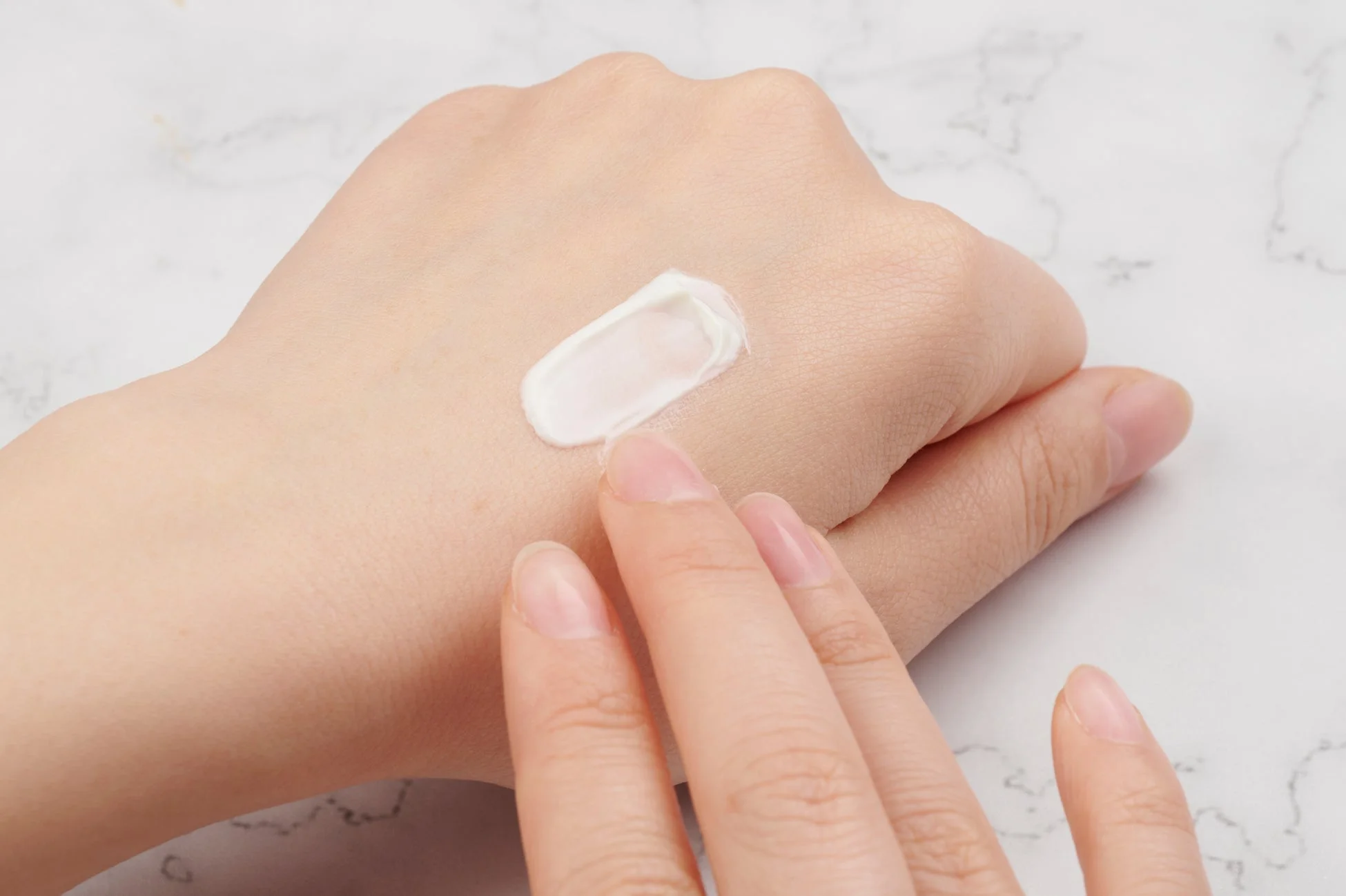 手にクリームを塗る女性