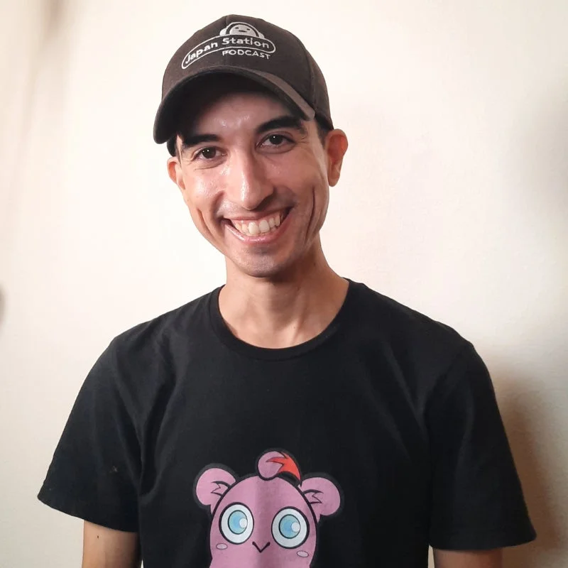 ポッドキャストのロゴが入ったキャップを被り笑顔の男性