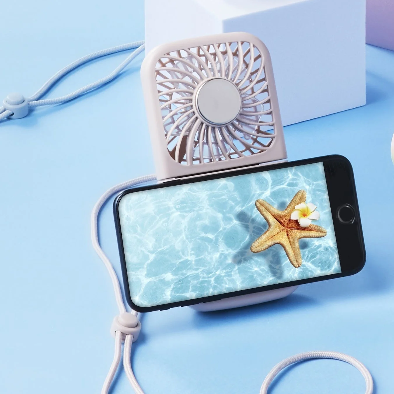 スマートフォンに装着された淡いピンク色の携帯扇風機