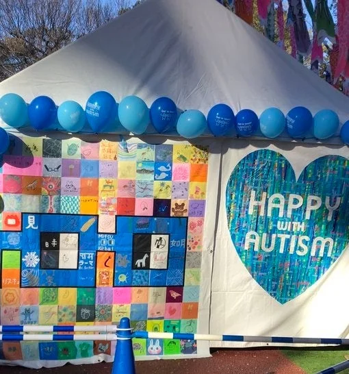 「HAPPY WITH AUTISM」のメッセージが描かれたアートテント