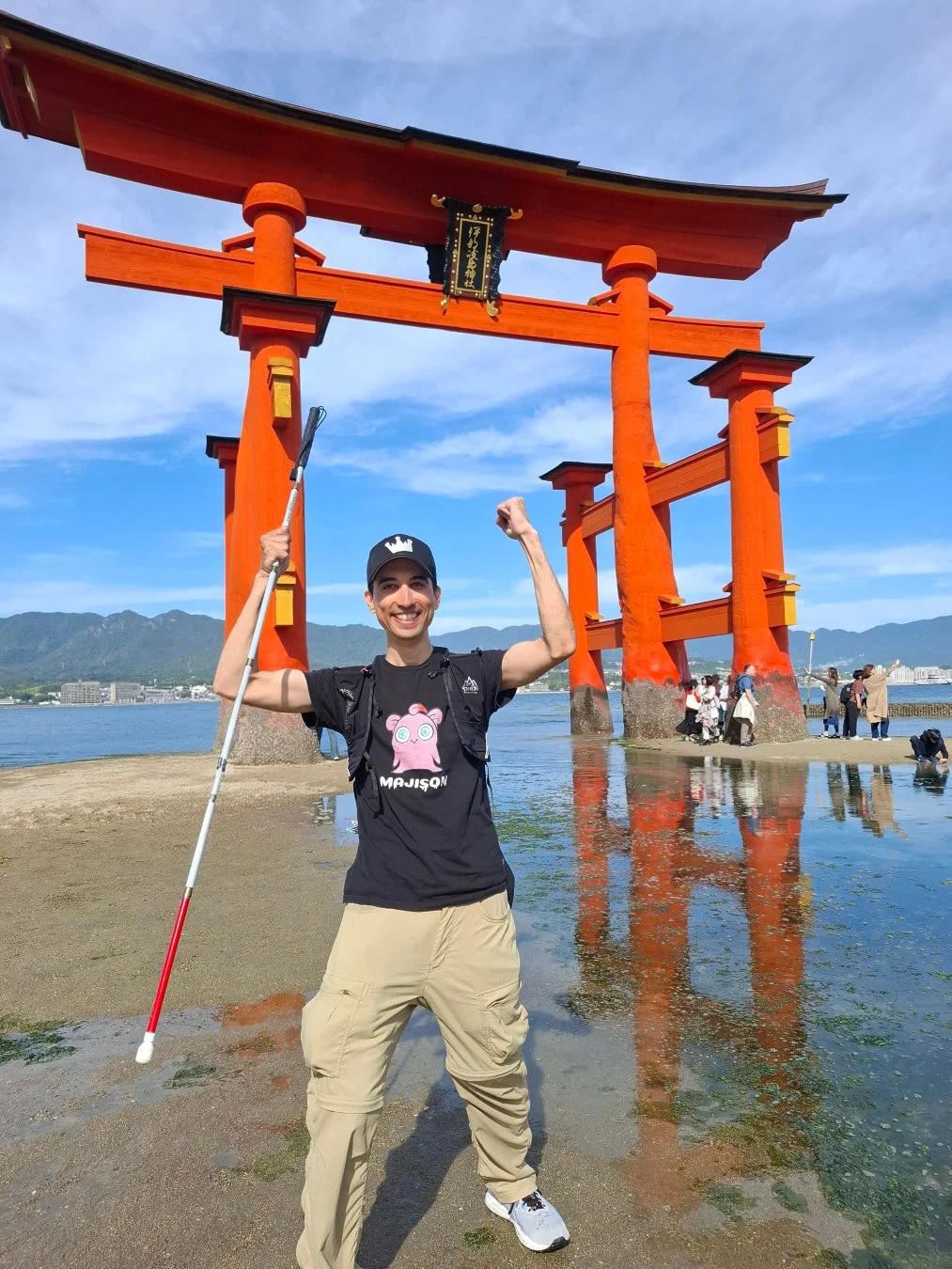 厳島神社の大鳥居の前で笑顔の男性