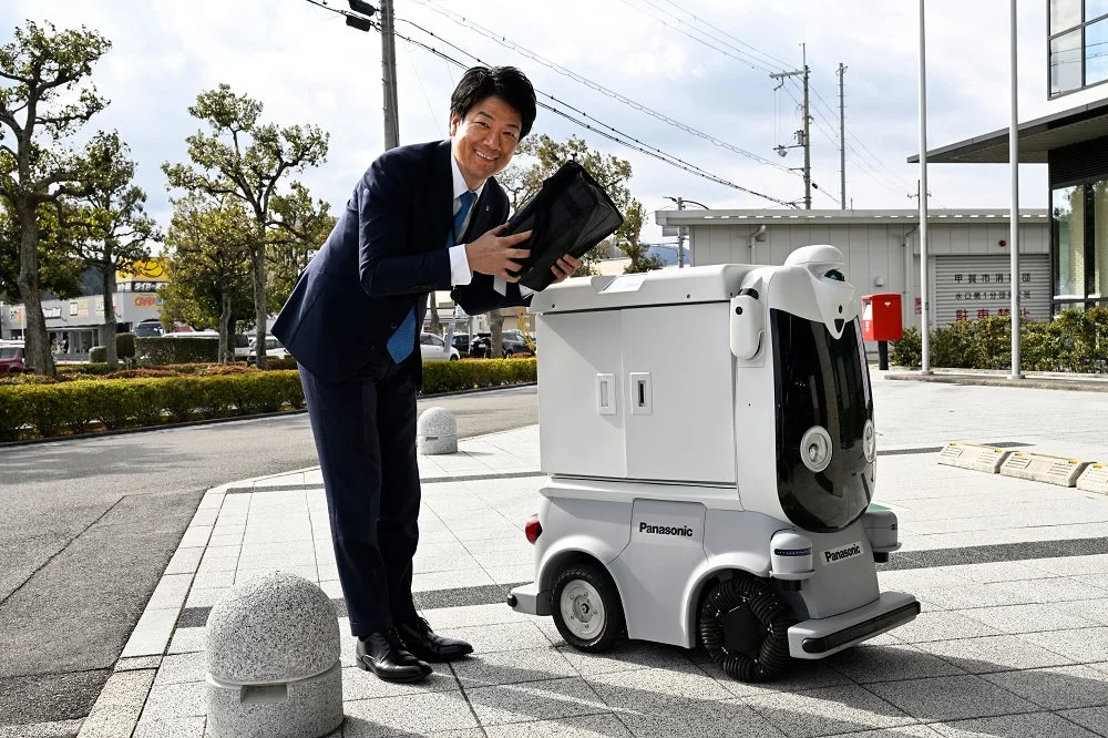 男性が自動配送ロボットに荷物を入れている様子