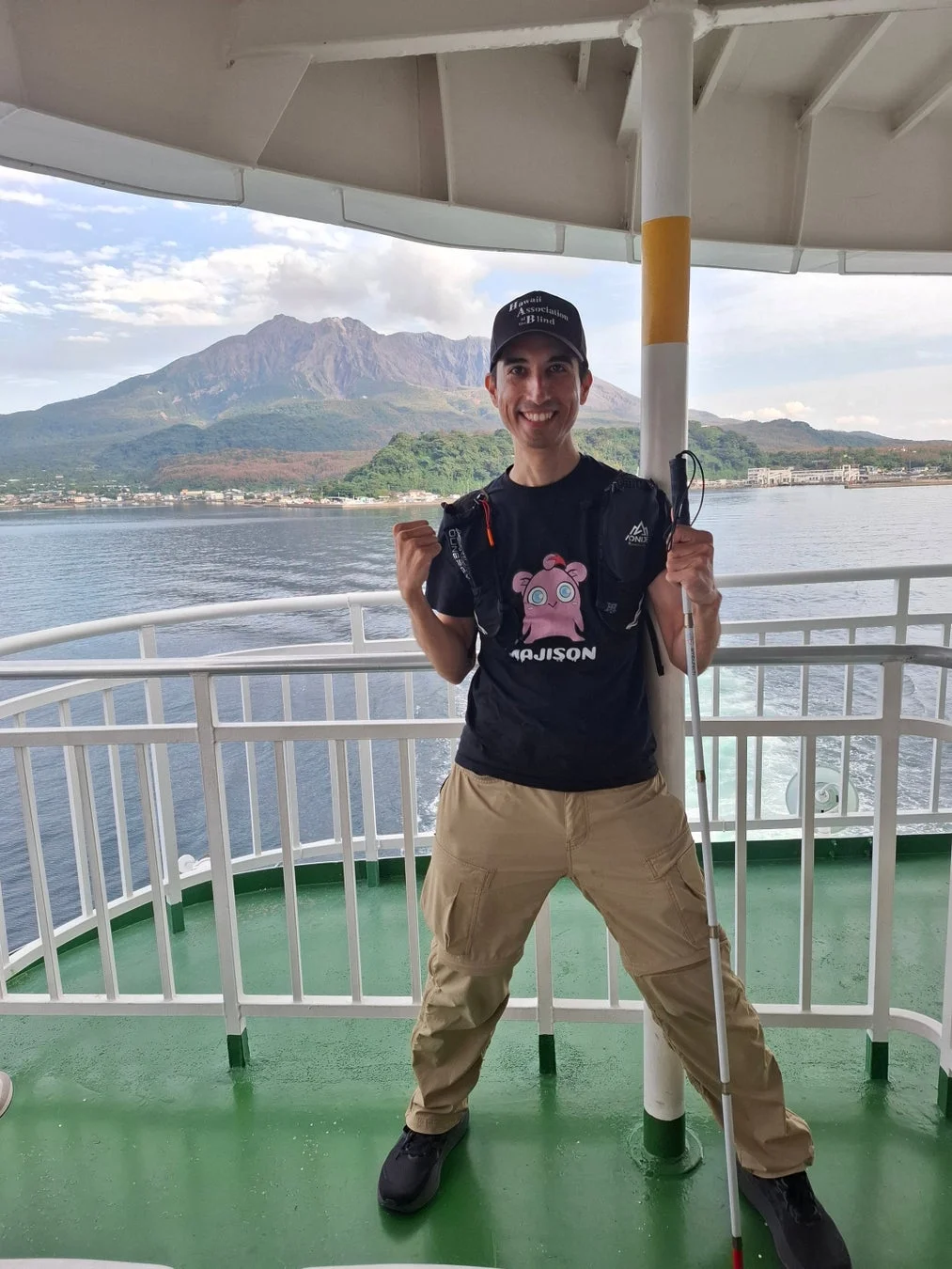 フェリーのデッキで桜島を背景に笑顔の男性