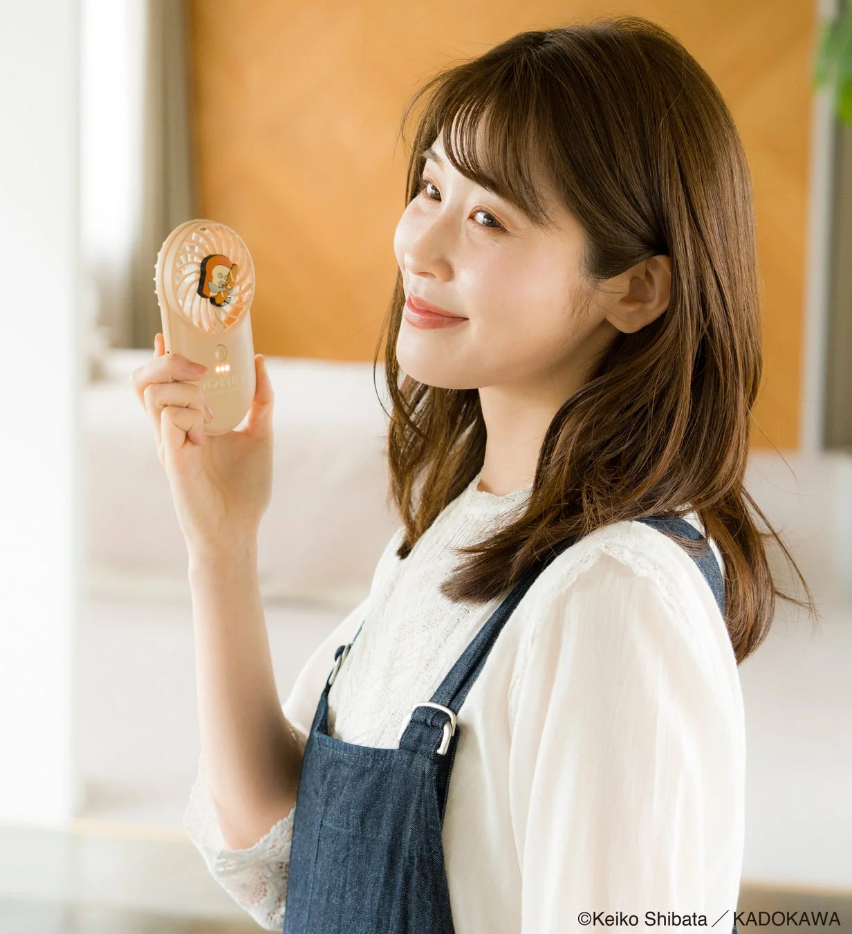 軽量・薄型ハンディーファンを持つ女性