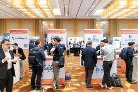 多くの人々が参加し、複数の企業ブースが並ぶビジネス展示会の様子