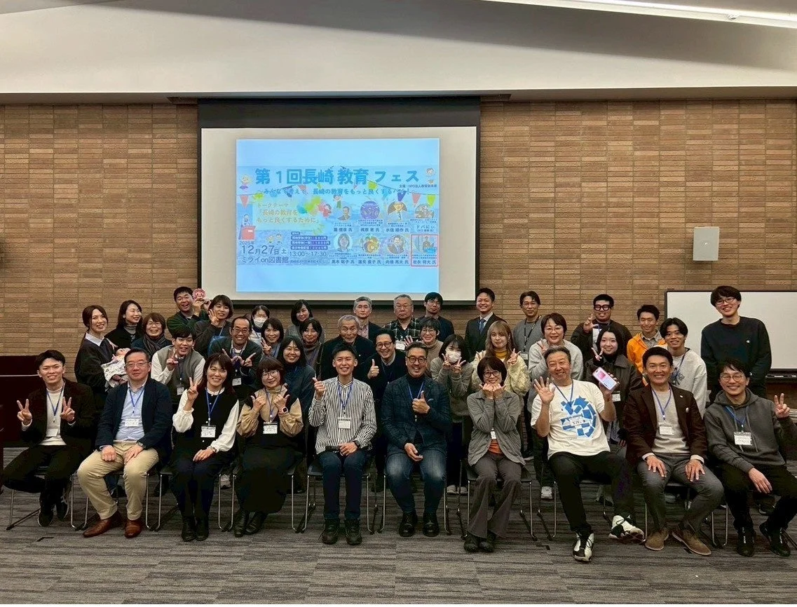 「第1回長崎教育フェス」のイベント会場で、多数の参加者が集合写真を撮影している様子