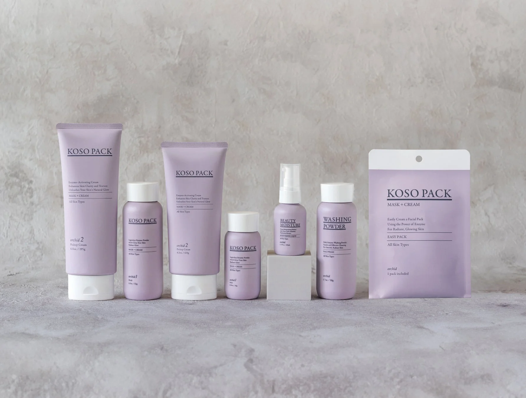 薄紫色のKOSO PACKスキンケア製品が複数並べられた画像です。酵素活性化クリーム、洗顔パウダー、保湿液、マスクなど、様々な種類の美容製品が含まれており、肌の輝きと質感を高めることを目的としています。