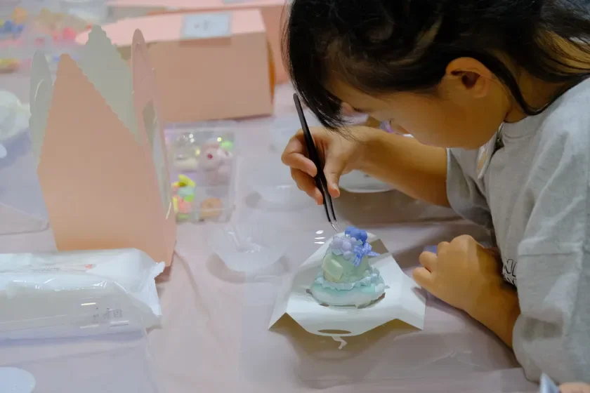 パステルカラーのミニチュアスイーツをデコレーションする子供
