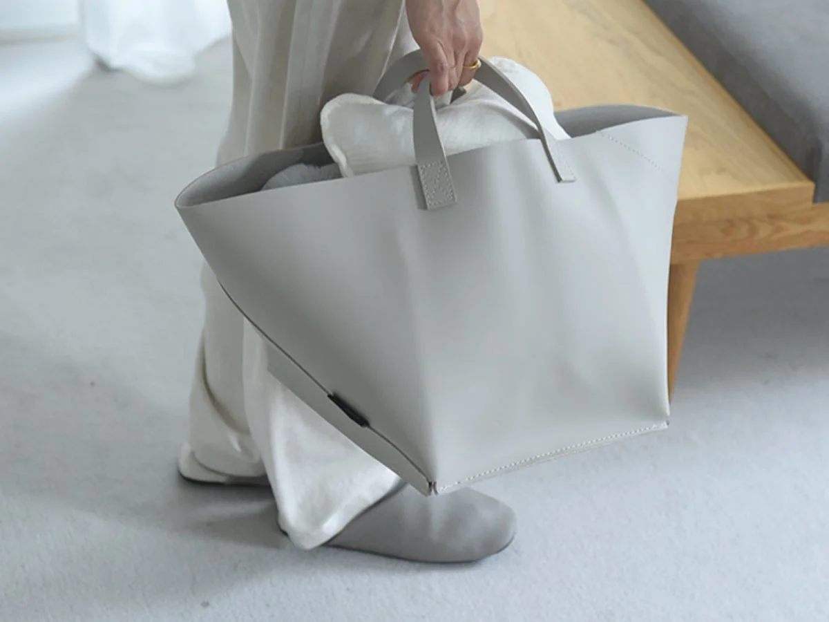 大きなグレーのトートバッグを持った人物