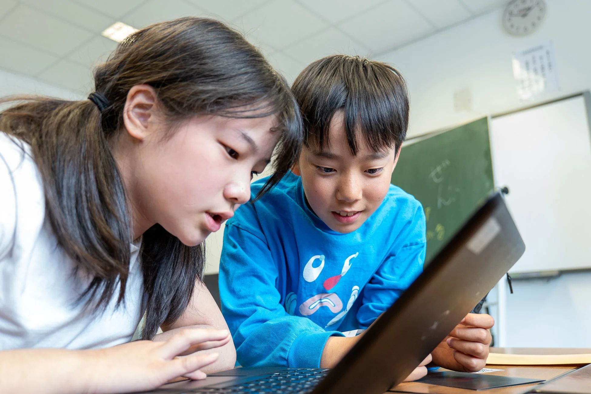 子供たちがノートパソコンを見つめる様子
