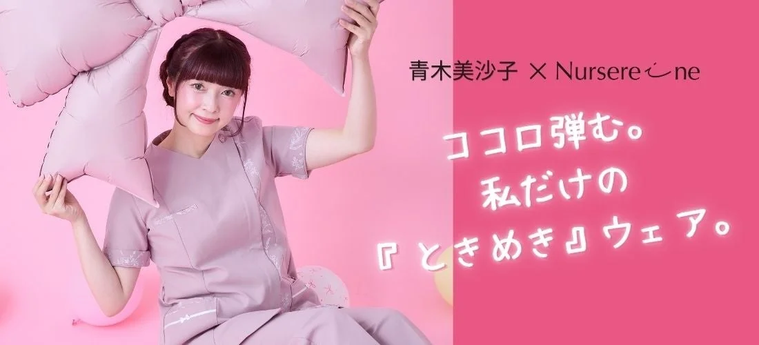 青木美沙子さんがスクラブを着て笑顔でリボン型クッションを持つ画像