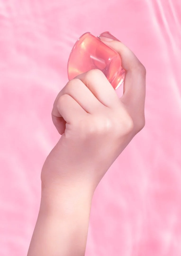 手のひらでピンクのグミを握る様子