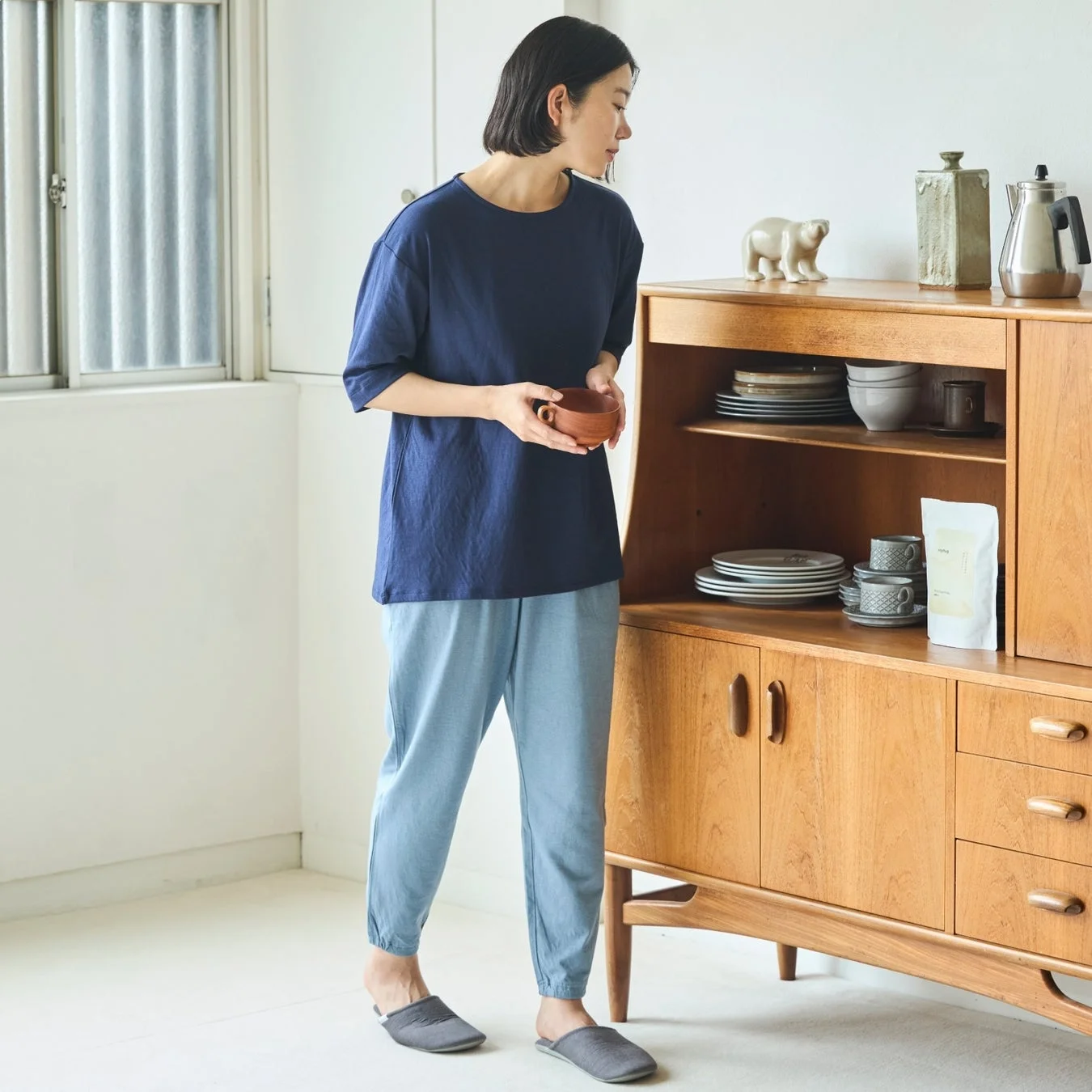 女性が木製キャビネットの食器を見ている様子