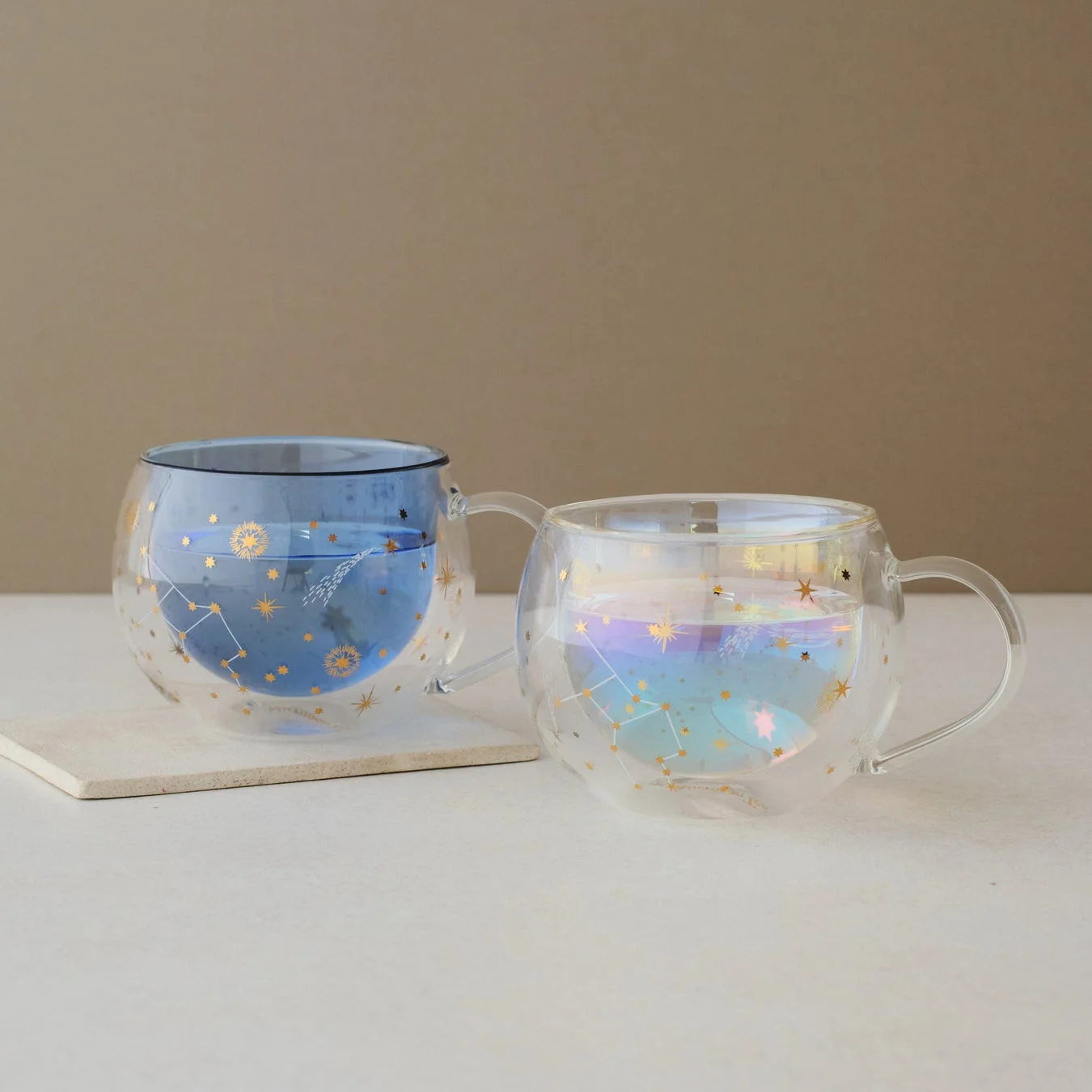 星や星座のモチーフが施された、二重構造のガラス製マグカップが2つ並べられています。