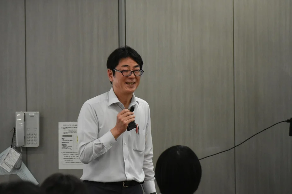 マイクを持って笑顔で話すたけぞう氏