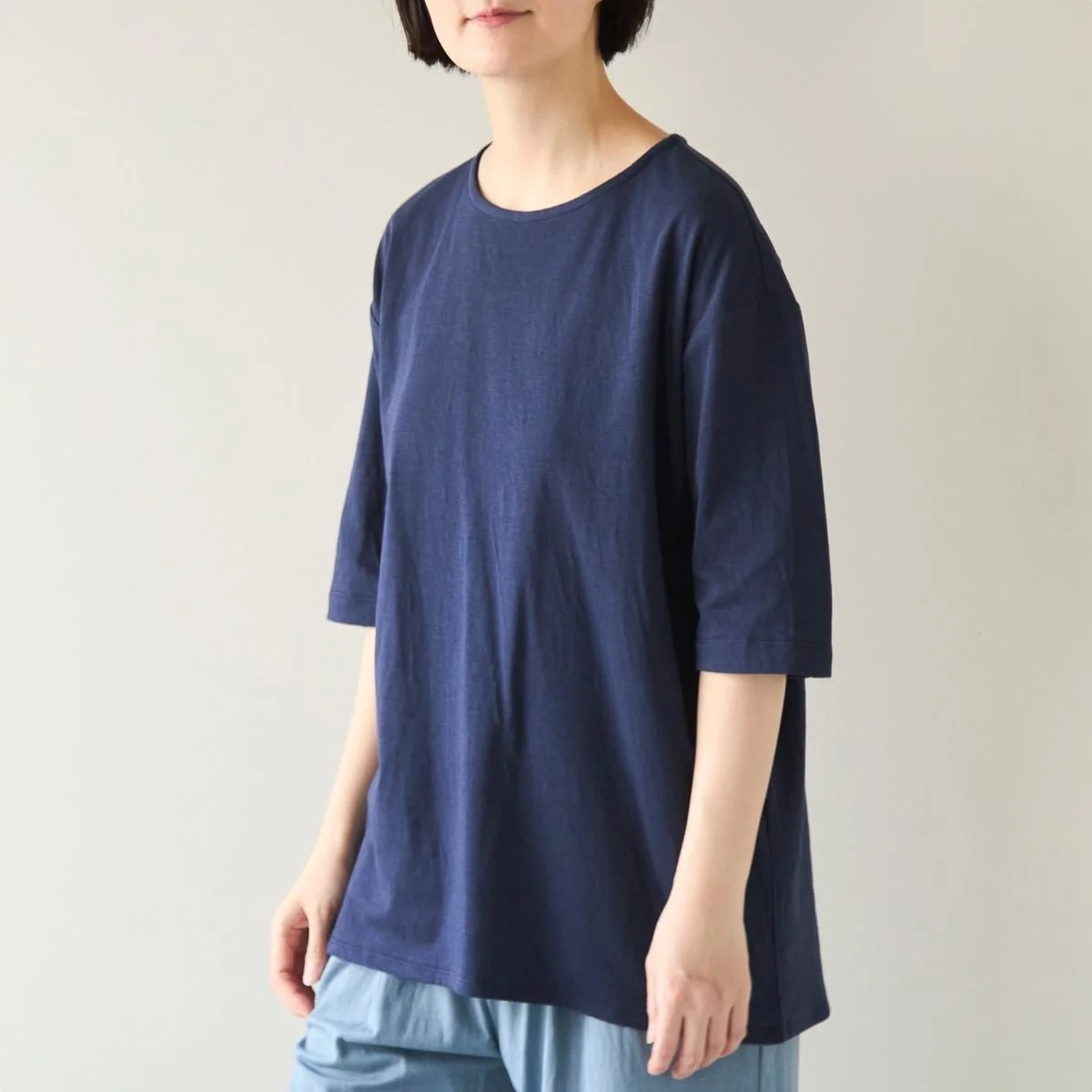 紺色のゆったりとしたTシャツと水色のパンツを着用した人物のポートレート