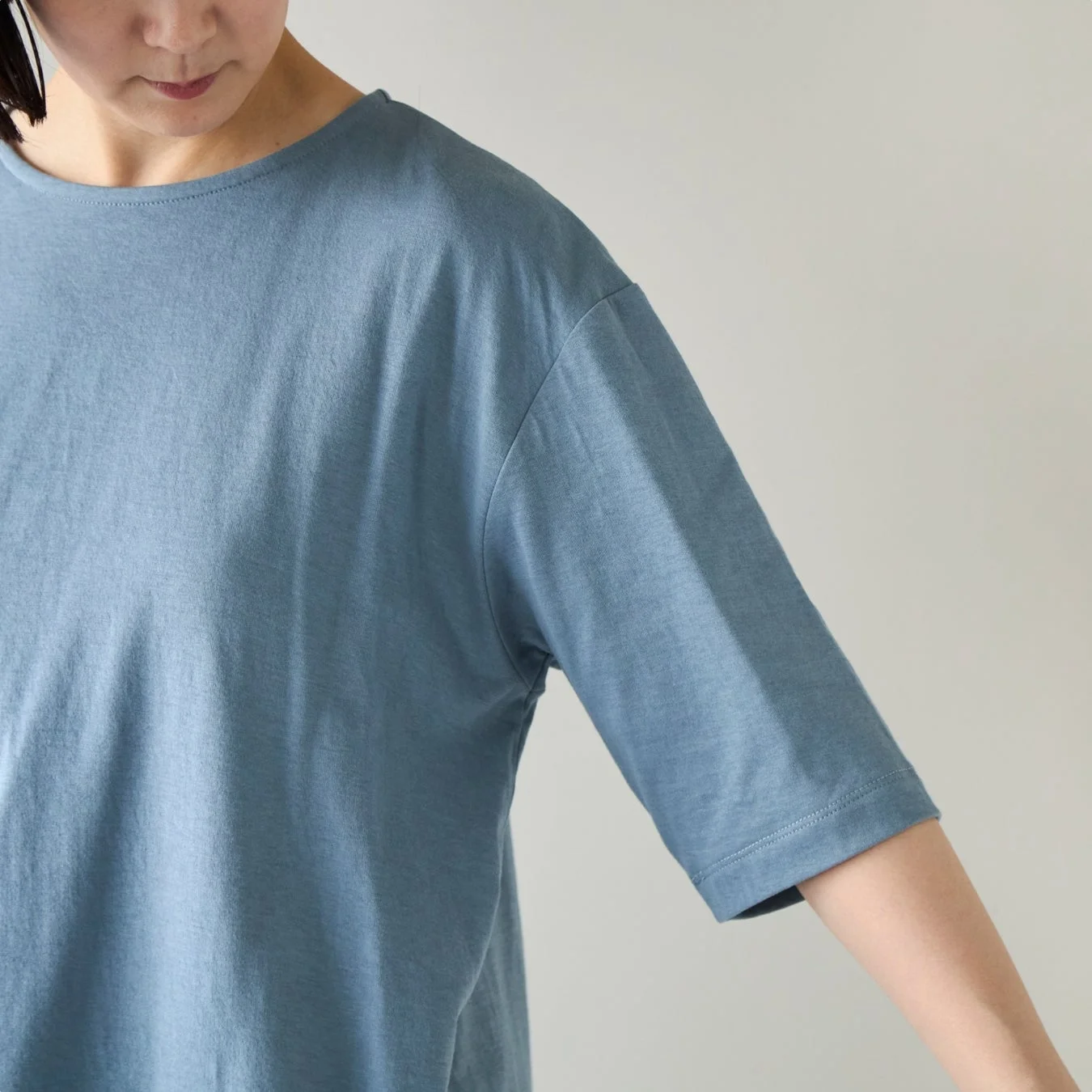 無地の青いTシャツを着た女性の上半身