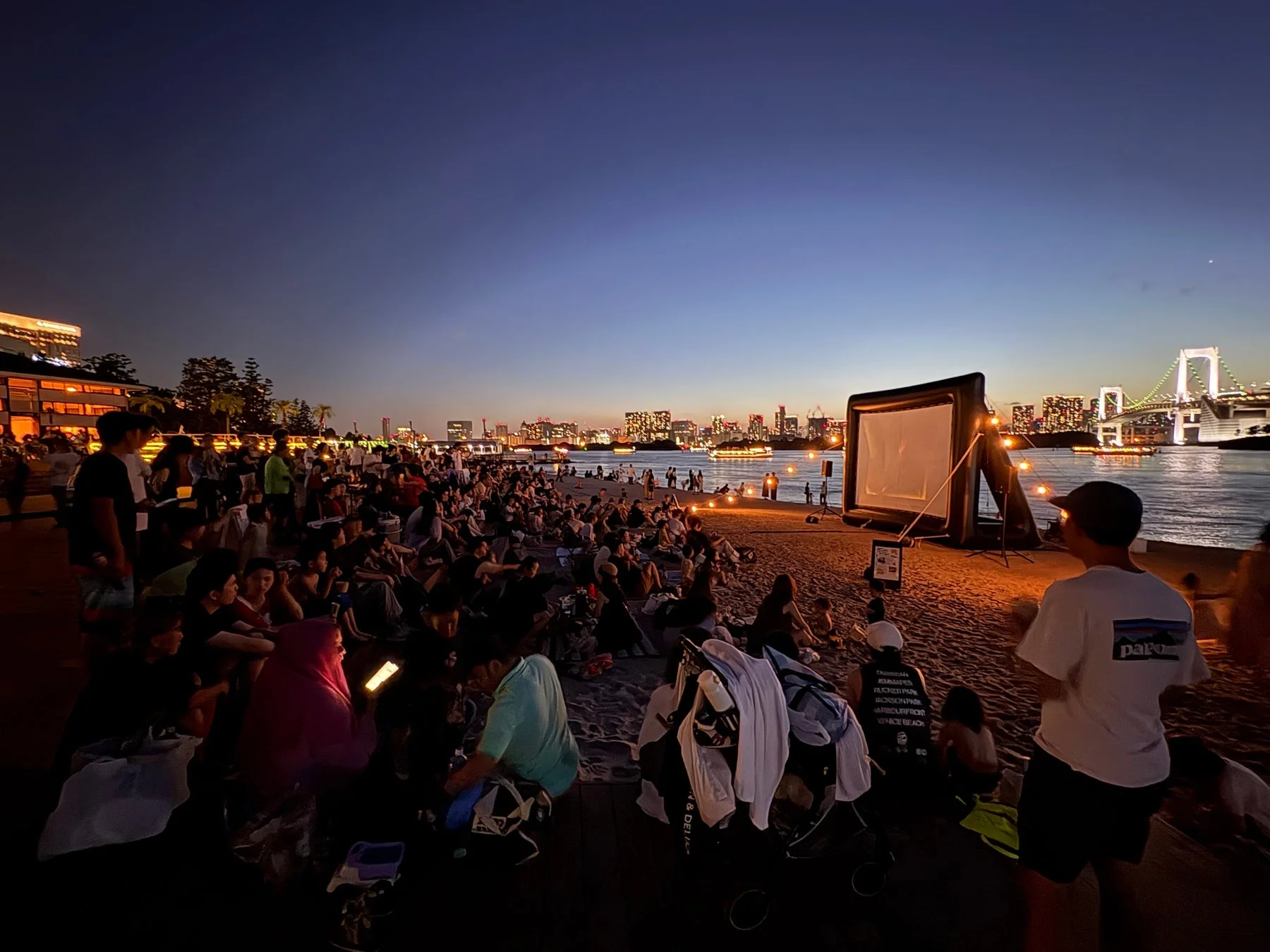 夕暮れのビーチで屋外映画を楽しむ人々