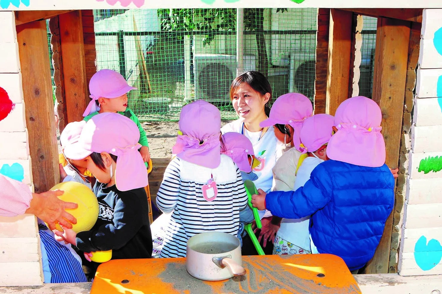 保育園で砂場遊びをする子供たちと保育士